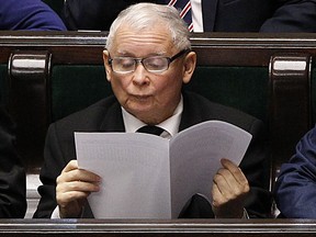 Jaroslaw Kaczynski, leader of the country's ruling Law and Justice party, reads, in parliament in Warsaw, Poland, Friday, Nov. 24, 2017. Poland's most powerful politician openly read a book about cats during a session of parliament Friday, setting off a slew of jokes but also accusations that he was trying to distract voters from a controversial overhaul of the judicial system. (AP Photo/Czarek Sokolowski)