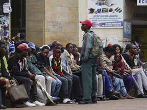 Zimbabweans queue outside a bank to withdraw cash as armed soldiers patrol the streets in Harare, Wednesday, Nov. 15, 2017.  In an extraordinary statement after taking over the state broadcaster during a night of unrest, Zimbabwe's army said early Wednesday it was only targeting "criminals" around President Robert Mugabe, and sought to reassure the country that "this is not a military takeover." (AP Photo)