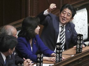 Japanese Prime Minister Shinzo Abe, right, gestures as he talks with other lawmakers during an extraordinary session at the parliament's lower house in Tokyo Wednesday, Nov. 1, 2017. Abe is expected to be re-elected as prime minister, following his ruling coalition's victory in the Oct. 22 elections. (AP Photo/Eugene Hoshiko)