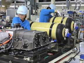 In this Oct. 30, 2017, photo, workers of Toyota Motor Corp. set hydrogen-stored tanks, in yellow, to be placed into a Mirai fuel cell vehicle at the automaker's Motomachi plant, in Toyota, western Japan. Toyota is banking on a futuristic "electrification" auto technology called hydrogen fuel cells for its zero-emissions option. The Associated Press got a tour of Toyota's Motomachi plant that assembles the Mirai fuel cell vehicle. (AP Photo/Yuri Kageyama)