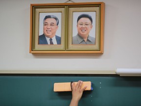 In this Sept. 26, 2017 photo, a student cleans the blackboard under the portraits of the late North Korean leaders Kim Il Sung and Kim Jong Il hanging on the classroom wall at a Tokyo Korean high school in Tokyo.  Many third- and fourth-generation descendants of Koreans brought to Japan during the imperialist years before and during World War II remain loyal to their roots. Families send children to private schools that favor North Korea and teach the language, culture and history of their ancestry. Despite recent North Korean missile launches and nuclear tests, students say they take pride and view their community as a haven from the discrimination they face from ethnic Japanese. (AP Photo/Eugene Hoshiko)