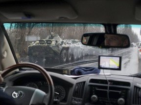 In this OSCE monitoring mission photo taken Tuesday, Nov. 21, 2017, in Ukraine's eastern city of Luhansk, APCs and armed men drive in the city center. Dozens of armed people in combat fatigues have deployed Wednesday, Nov. 22, to main administrative buildings in Luhansk, a major city in rebel-controlled territories in eastern Ukraine, in a sign of a split in the rebel leadership. (OSCE SMM via AP)