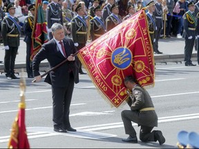 FILE - In this Thursday, Aug. 29, 2017 file photo, Ukraine's President Petro Poroshenko, left, hands over the flag of a military unit as an officer kisses it, during a military parade to celebrate Independence Day in Kiev, Ukraine. Former Georgian President Mikhail Saakashvili, who now heads a Ukrainian opposition party, has organized a series of street protests against President Petro Poroshenko, accusing him of stalling reforms and covering up corruption.(AP Photo/Efrem Lukatsky)(AP Photo/Efrem Lukatsky, FILE)