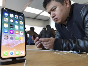 In this Tuesday, Nov. 7, 2017, photo, a shopper looks at the latest iPhone X from U.S. tech giant Apple at a retail store in Beijing, China. After a brief truce with China to cooperate over North Korea, U.S. President Donald Trump visits Beijing this week amid mounting U.S. trade complaints, with limited prospects for progress on market access, technology policy and other sore points. The strains between the world's two biggest economies are fueling anxiety among global companies and advocates of free trade that they could retreat into protectionism, dragging down growth. (AP Photo/Ng Han Guan)