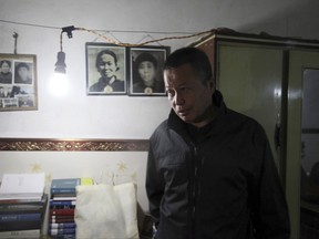 FILE - In this 2015, file photo, Gao Zhisheng walks past photos of his relatives in a cave home where he is confined in northwestern China's Shaanxi province. Gao's whereabouts are now unknown after a short lived escape from his state security captors. Gao's plight shows what activists say is a drastically deteriorating situation for rights campaigners under the rule of President Xi Jinping, who emerged from a party congress last month as the most powerful Chinese leader in a generation. (AP Photo/Paul Traynor, File)