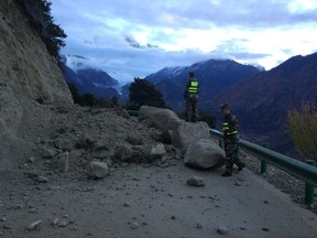 In this photo released by China's Xinhua News Agency, rescuers look at a road blocked by fallen rocks in Paizhen town in Mainling county of Nyingchi city in southwestern China's Tibet Autonomous Region, Saturday, Nov. 18, 2017. A strong earthquake has shaken China's Tibet region. The U.S. Geological Survey says the 6.3 magnitude quake hit at a depth of about 6 miles (10 kilometers) about 36 miles (58 kilometers) northeast of Nyingchi. (Liu Pengchao/Xinhua via AP)