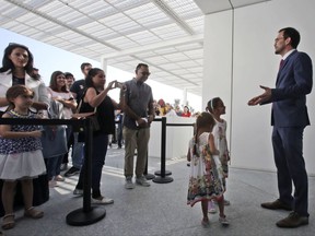 The president-director of the Louvre Museum, Jean-Luc Martinez, right, welcomes the two daughters of a family as the first guests at the Louvre Museum in Abu Dhabi, United Arab Emirates, Saturday, Nov. 10, 2017. The Louvre Abu Dhabi has opened to the public after a decade-long wait and questions over laborers' conditions working on the project.  (AP Photo/Kamran Jebreili)