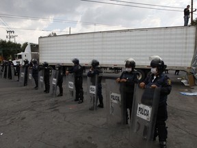FILE - In this Sept. 1, 2010 file photo, police wearing face-masks guard a truck that arrived carrying the bodies of some of the 72 migrants who were killed in northern Mexico while trying to reach the US border, at a funeral home in Mexico City. Prosecutors said police and military personnel arrested on Tuesday, Nov. 14, 2017 an "old school" Zetas leader Martiniano Jaramillo who allegedly coordinated the 2010 killing spree that included the massacre of 72 Central American migrants in San Fernando in the border state of Tamaulipas. (AP Photo/Eduardo Verdugo, File)