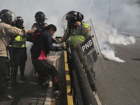 FILE - In this May 20, 2017 file photo, Venezuelan state security forces detain a protester amid tear gas during a demonstration by opponents of President Nicolas Maduro blocking a major highway in Caracas, Venezuela. According to Human Rights Watch on Wednesday, Nov. 29, 2017, state security forces systematically abused opposition protesters detained during months of deadly political unrest earlier this year, in what the rights group described as a level of repression "unseen in Venezuela in recent memory." (AP Photo/Fernando Llano, File)
