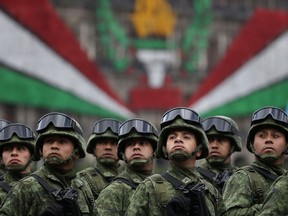 FILE - In this Sept. 16, 2016 file photo, soldiers look up toward the president as they ride past the National Palace during the annual Independence Day military parade in Mexico City's main square, known as the Zocalo. A bill to give legal justification for Mexico's armed forces to assume police roles advanced in the country's Congress, Thursday, Nov. 30, 2017, over objections by rights groups and opposition legislators who say it would provide for an open-ended militarization.  (AP Photo/Rebecca Blackwell, File)