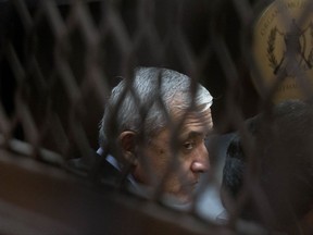 FILE - In this Sept. 8, 2015 file photo, Guatemala's former President Otto Perez Molina, photographed through a window, sits in court for a third hearing on corruption allegations that led him to resign, in Guatemala City. A Human Rights Watch report published on Sunday, Nov. 12 2017, says that Guatemala's judicial system is putting its ongoing fight against corruption in jeopardy, as in the the case against Perez Molina. (AP Photo/Esteban Felix, File)