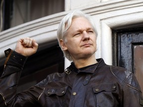 FILE - In this May 19, 2017 file photo, Julian Assange greets supporters outside the Ecuadorian embassy in London. Ecuador's government released a statement Wednesday, Nov. 22, once again calling on Assange to not intervene in the affairs of other countries following Spanish complaints about his contacts with Catalan secessionists, though it said the Wikileaks founder would continue enjoying political asylum in its London embassy. (AP Photo/Frank Augstein, File)