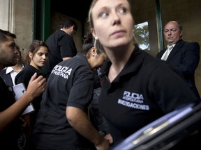 FILE - In this Tuesday, Jan. 20, 2015, file photo, police enter the building where late prosecutor Alberto Nisman had his office, to gather evidence for the investigation into his death in Buenos Aires, Argentina. A new report, whose conclusions are based on controversial new evidence, was obtained by The Associated Press, reverses the earlier official findings that Nisman had likely committed suicide. (AP Photo/Rodrigo Abd,File, File)