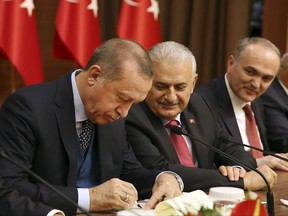 Turkey's President Recep Tayyip Erdogan left, takes notes as Turkey's Prime Minister Binali Yildirim, centre, looks on, during a event in Ankara, Turkey, Thursday, Nov. 2, 2017. (Yasin Bulbul/Pool Photo via AP)