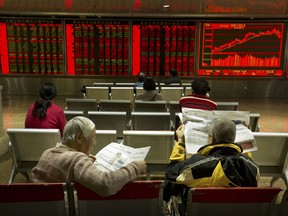 Chinese investors read newspapers as they monitor stock prices at a brokerage house in Beijing, Thursday, Nov. 30, 2017. Asian stock markets declined Thursday after U.S. tech stocks fell and China reported stronger manufacturing as investors looked ahead to a key OPEC meeting. (AP Photo/Mark Schiefelbein)