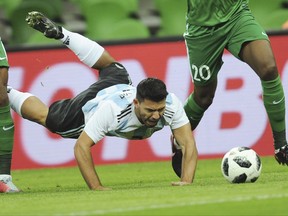 Argentina's Sergio Aguero, center, falls down as he challenges for the ball with Nigeria's Chidozie Awaziem, right, and John Obi Mikel, left, during the international friendly soccer match between Argentina and Nigeria in Krasnodar, Russia, Tuesday, Nov. 14, 2017. (AP Photo/Sergey Pivovarov)