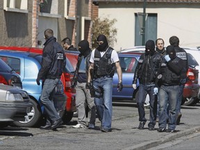FILE - In this March 23 2012 file photo, police officers search for clues outside Mohamed Merah's apartment building in Toulouse, southwestern France. Once nicknamed Bin Laden in the French housing project where he grew up, the violence-prone ex-delinquent Abdelkader Merah, brother of Mohamed Merah, now says he is a peaceful Muslim and has displayed calm, wit and knowledge at his terror trial in Paris. (AP Photo/Remy de la Mauviniere, File)