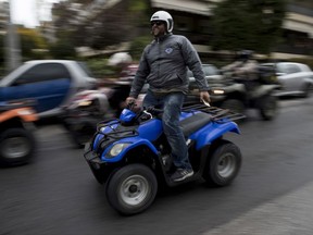 A protester drives his all-terrain vehicle, ATV, during a rally outside Greek Transport Ministry in Athens, Monday, Nov. 13, 2017. Hundreds of four-wheel motorbike owners, most from Greek holiday resorts, have blocked traffic outside the country's Transport Ministry to protest a proposed vehicle ban. (AP Photo/Petros Giannakouris)