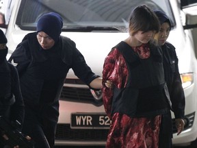 Vietnamese Doan Thi Huong, second right, is escorted by police as she arrives for court hearing at Shah Alam court house in Shah Alam, outside Kuala Lumpur, Malaysia, Wednesday, Nov. 8, 2017. A police officer testified Monday at the trial of two women accused of killing Kim Jong Nam, the half brother of North Korea's leader that four suspects at large believed to have plotted with the women were North Koreans who fled Malaysia immediately after the assassination. (AP Photo/Sadiq Asyraf)