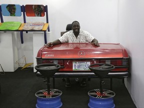 In this photo taken Friday, Nov. 10, 2017, a man sits on an art work named ''Arthouse Contemporary" by Nigerian artist Diseye Tantua, who creates art pieces using car parts, during the African Culture and Design Festival in Lagos, Nigeria. Africa's most populous city is aiming to become a cultural hub for the continent, as the boisterous city of Lagos hosted the AFRICAN Culture and Design festival. (AP Photo/Sunday Alamba )