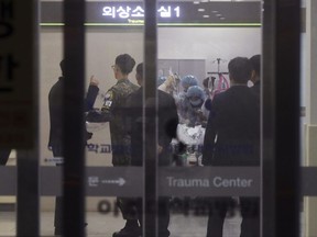 FILE - in this Nov. 13, 2017, file photo, a South Korean army soldier, second from left, is seen as medical members treat an unidentified injured person, believed to be a North Korean soldier, at a hospital in Suwon, South Korea. Hospital officials say on Saturday, Nov. 18, 2017, the condition of a North Korean soldier severely wounded by gunfire while escaping to South Korea is gradually improving after two surgeries but it's too early to tell whether he makes a recovery. (Hong Ki-won/Yonhap via AP, File)