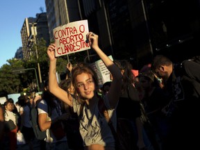 A woman holds up a sign that reads in Portuguese: "Against clandestine abortion" to protest a recent congressional committee vote to make abortion illegal without exception nationwide, in Rio de Janeiro, Brazil, Monday, Nov. 13, 2017. Abortion is currently allowed in cases of rape, a pregnancy that threatens a woman's life or a fetus with anencephaly, but lawmakers adopted a measure that would remove those exceptions which would need a super-majority in both Congress' lower house and the Senate to become law. (AP Photo/Silvia Izquierdo)
