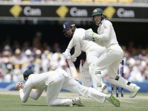 Australia's Steve Smith, left, dives to take a catch to get the wicket of England's Mark Stoneman, center, during their Ashes cricket test in Brisbane, Australia, Sunday, Nov. 26, 2017. (AP Photo/Tertius Pickard)