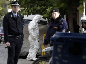 A Greek police expert investigates a house as his colleagues secure the area after an operation in Athens, Tuesday, Nov. 28. 2017. Greek counter-terrorism police detained nine Turks in Athens early Tuesday in an investigation connected with Turkish leftist militant groups, ahead of a scheduled visit by Turkey's President Recep Tayyip Erdogan. (AP Photo/Thanassis Stavrakis)