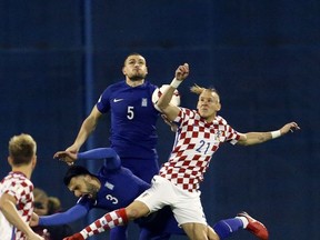 Greece's Kyriakos Papadopoulos, center, his teammate Giorgos Tzavelas, left, and Croatia's Domagoj Vida, right, jump for the ball during the World Cup qualifying play-off first leg soccer match between Croatia and Greece at Maksimir Stadium in Zagreb, Thursday Nov. 9, 2017. (AP Photo/Darko Bandic)