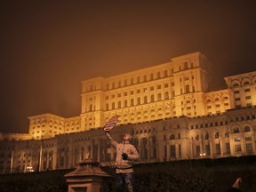 A woman holds a sign that reads "All for Justice" backdropped by the communist era build House of the People, now headquarters of Romania's parliament, during a protest in Bucharest, Romania, Sunday, Nov. 26, 2017. Thousands have protested in Romania's capital and other major cities against planned changes to the justice system they say will allow high-level corruption to go unpunished and a tax overhaul that could lead to lower wages.(AP Photo/Vadim Ghirda)