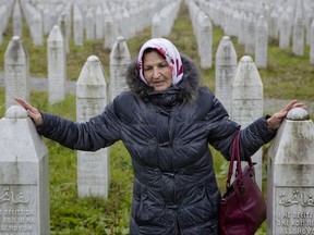 In this Thursday, Nov. 16, 2017, photo, a woman touches grave stones at the memorial center of Potocari near Srebrenica, Bosnia. As a U.N court prepares to hand down its verdict in the case against Ratko Mladic, the Bosnian Serb military leader during the Balkan country's 1992-5 war, the remains of numerous victims of genocide and war crimes of which he stands accused still await identification. (AP Photo/Amel Emric)