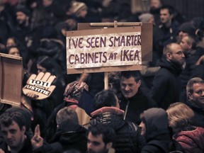 A man holds a banner during a protest in Bucharest, Romania, Sunday, Nov. 26, 2017. Thousands have protested in Romania's capital and other major cities against planned changes to the justice system they say will allow high-level corruption to go unpunished and a tax overhaul that could lead to lower wages.(AP Photo/Vadim Ghirda)