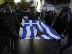 University students hold a blood-stained Greek flag from the deadly 1973 student uprising, in Athens on Friday, Nov. 17, 2017. Several thousand people march to the U.S. Embassy in Athens under tight police security to commemorate a 1973 student uprising that was crushed by Greece's military junta, that ruled the country from 1967-74. (AP Photo/Thanassis Stavrakis)