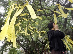 A Taiwanese supporter kisses a yellow ribbon to pray during a media event to support Taiwanese activist Lee Ming-che detained in China, in Taipei, Taiwan, Tuesday, Nov. 7, 2017. Taiwanese human rights activists are calling on U.S. President Donald Trump to ask for the release of Lee Ming-che charged with political crimes in China during his visit to Beijing this week. (AP Photo/Chiang Ying-ying)