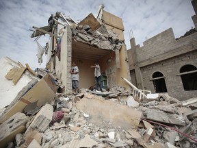 FILE - In this Aug. 25, 2017 file photo, boys stand on the rubble of a house destroyed by Saudi-led airstrikes in Sanaa, Yemen. The Saudi-led coalition fighting in Yemen is blaming a rebel missile launch on Iran and warning it could be "considered as an act of war." Early Monday, Nov. 6, 2017, the coalition also closed off the land, sea and air ports to the Arab world's poorest country over the missile launch targeting Riyadh. (AP Photo/Hani Mohammed, File)