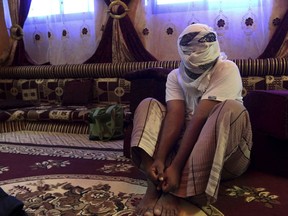FILE -- In this May 11, 2017 photo, a former detainee covers his face for fear of being detained again, as he shows how he was kept in handcuffs and leg shackles while held in a secret prison at Riyan airport in the Yemeni city of Mukalla. A senior Yemeni official and families of prisoners said on Monday, Nov. 13, 2017,  that dozens of detainees have been moved to a government-run prison in the southern city of Mukalla. The official told The Associated Press that 133 detainees were transferred from the Riyan airport. (AP Photo, File)