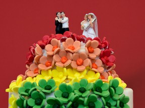 A wedding cake in rainbow colours and decorated with two same-sex couples.