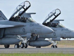 Royal Australian Air Force F-18 Hornet pilots wave to the crowd as they taxi down the runway after performing during the Australian International Airshow at the Avalon Airfield near Lara southwest of Melbourne on February 24, 2015.