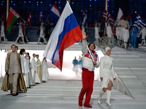 In this Feb. 23, 2014 file photo, figure skater Maxim Trankov carries the Russian flag into the closing ceremony of the Sochi Olympics.