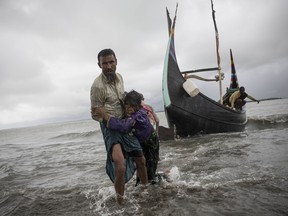A Rohingya man carries an elderly woman, after the wooden boat they were travelling on from Myanmar crashed into the shore and tipped everyone out on September 12, 2017 in Dakhinpara, Bangladesh.