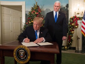U.S. President Donald Trump signs a proclamation after he delivered a statement on Jerusalem from the Diplomatic Reception Room of the White House in Washington, DC on December 6, 2017 as US Vice President Mike Pence looks on.