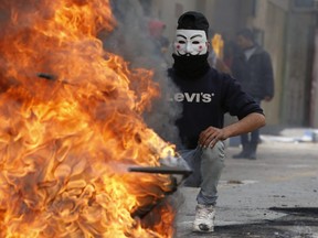 A Palestinian protester wears a Guy Fawkes mask used by the anonymous movement during clashes with Israeli troops on December 7, 2017 in Hebron in the Israeli-occupied West Bank, following protests against a decision by US President Donald Trump to recognize Jerusalem as the capital of Israel.