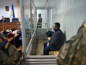 Stanislav Yezhov (C), a top government interpreter sits in a glass cage at the start of his hearing on suspicion of being a Russian spy at the courthouse in Kiev on December 22, 2017.