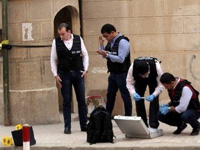 Egyptian security members and forensic police inspect the site of a gun attack outside a church south of the capital Cairo, on December 29, 2017. A gunman opened fire on a church, killing at least nine people before policemen shot him dead, state media and officials said.