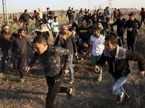 Palestinian protesters and medics evacuate a wounded youth during clashes on the Israeli border following a protest against U.S. President Donald Trump's decision to recognize Jerusalem as the capital of Israel, east of Gaza City, Friday, Dec. 8, 2017.