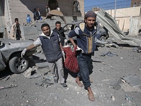 People carry the body of a man they uncovered from under the rubble of a Houthi-held detention center destroyed by Saudi-led airstrikes in Sanaa, Yemen, Wednesday, Dec. 13, 2017.