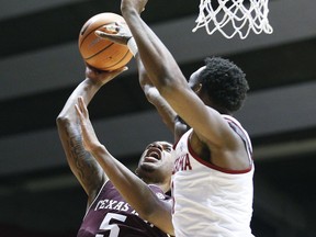 Texas A&M guard Savion Flagg, left, shoots against Alabama forward Donta Hall during the first half of an NCAA college basketball game Saturday, Dec. 30, 2017, in Tuscaloosa, Ala.