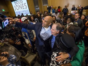U.S. Sen Cory Booker, D-N.J., and Democratic U.S. Senate candidate Doug Jones take selfies with supporters during a rally at Alabama State University in Montgomery, Ala. on Saturday, Dec. 9, 2017.