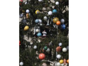 Framed by a Christmas tree, Pope Francis waves to faithful during the Angelus noon prayer he delivered from his studio window overlooking St. Peter's Square, at the Vatican, Sunday Dec. 3, 2017.
