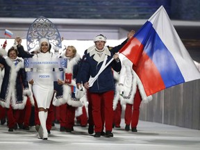 FILE - In this Feb. 7, 2014 file photo Alexander Zubkov of Russia carries the national flag as he leads the team during the opening ceremony of the 2014 Winter Olympics in Sochi, Russia. When the International Olympic Committee board prepares to vote Tuesday, Dec. 5, 2017 on whether to ban Russia from February's Winter Olympics, its members will decide the fate of numerous medals yet to be won.